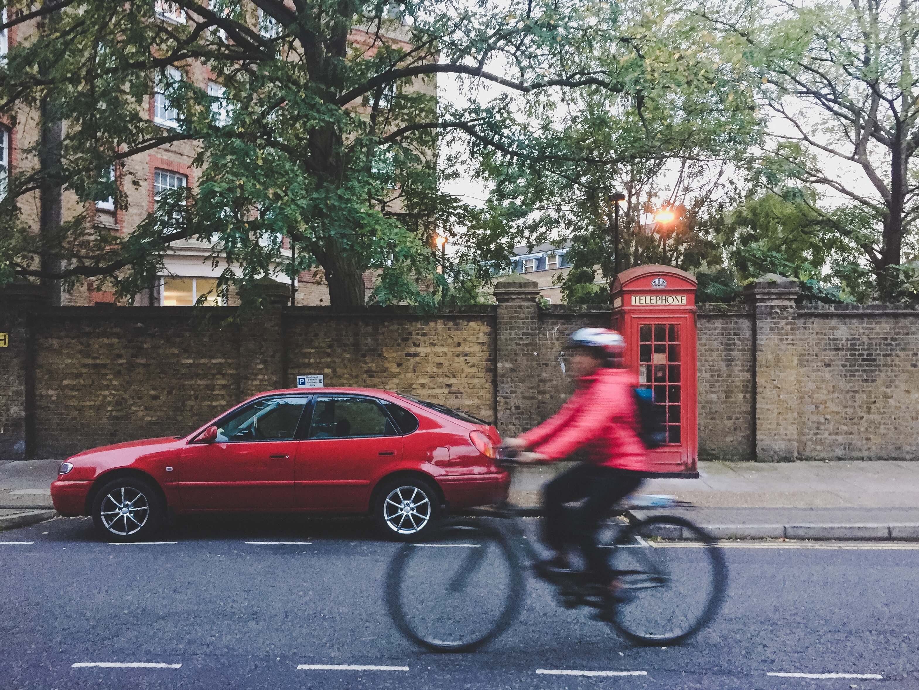 Árboles, bicicleta, coche y teléfono rojo en London Street